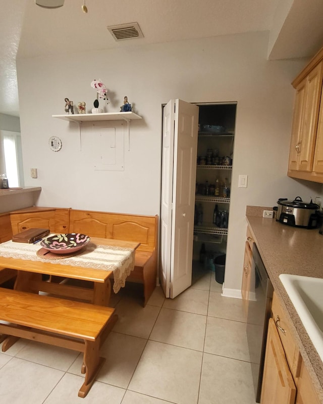 kitchen featuring visible vents, light brown cabinetry, dishwasher, light tile patterned flooring, and a sink