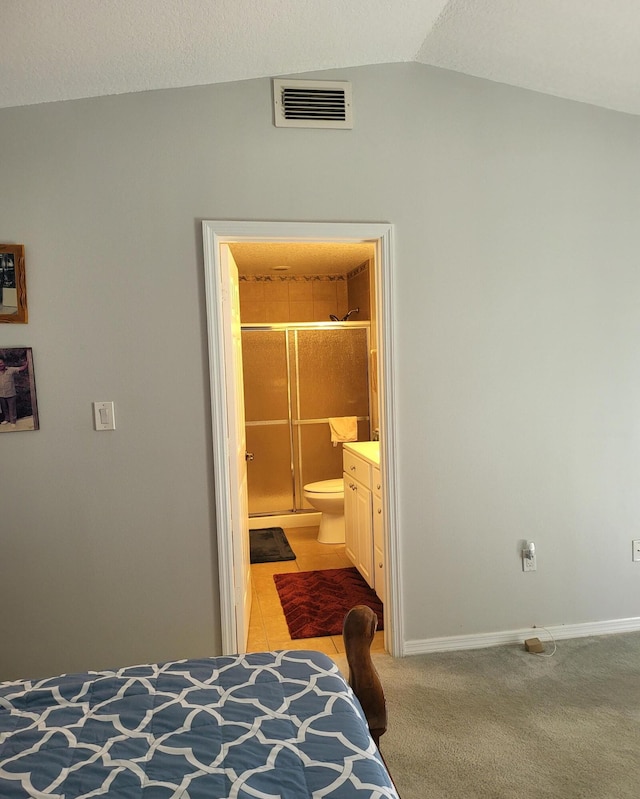 bedroom with visible vents, baseboards, light colored carpet, and connected bathroom