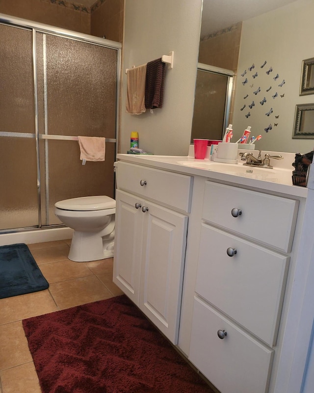 bathroom featuring tile patterned flooring, toilet, vanity, and a stall shower