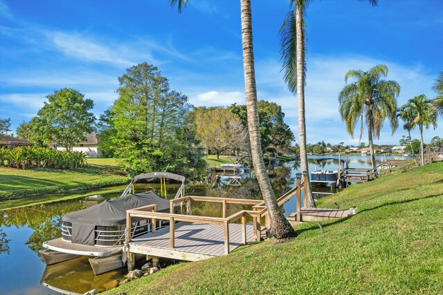 view of dock with a yard and a water view