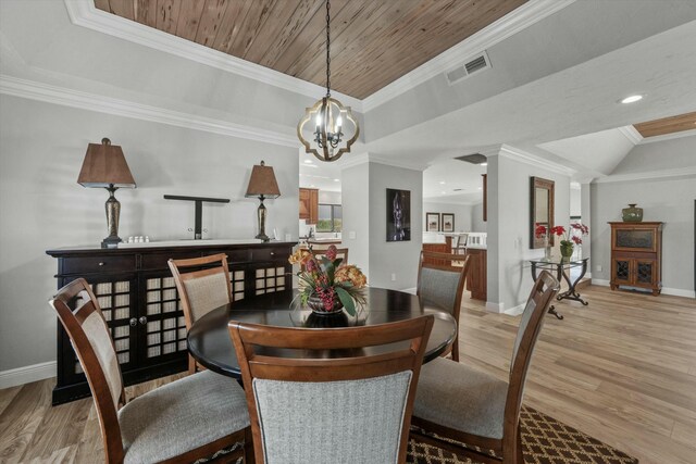 dining space featuring visible vents, baseboards, light wood-type flooring, ornamental molding, and a raised ceiling