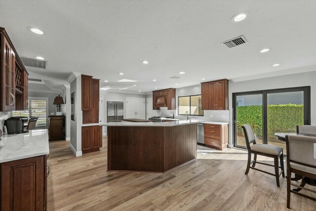 kitchen with visible vents, light wood-style floors, and ornamental molding