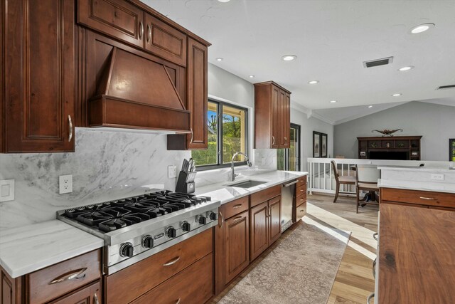 kitchen with premium range hood, visible vents, a sink, appliances with stainless steel finishes, and vaulted ceiling