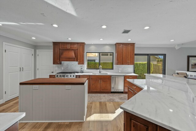 kitchen with visible vents, a kitchen island, light wood-style flooring, a sink, and stainless steel dishwasher