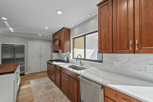 kitchen featuring premium range hood, recessed lighting, a sink, appliances with stainless steel finishes, and tasteful backsplash