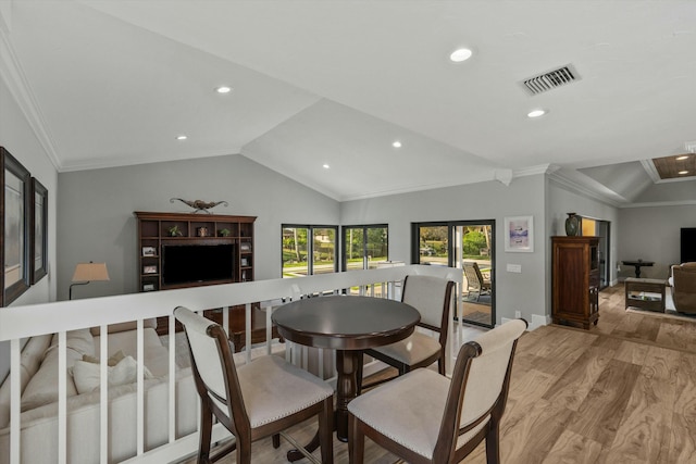 dining area featuring visible vents, light wood-style floors, lofted ceiling, and ornamental molding