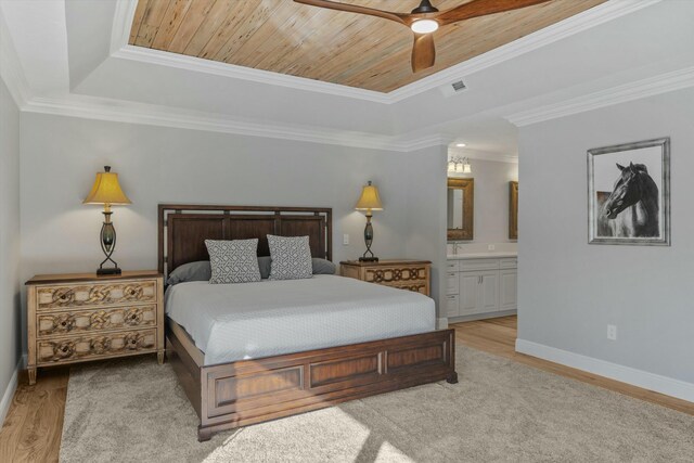 bedroom featuring light wood-style flooring, crown molding, a raised ceiling, and baseboards