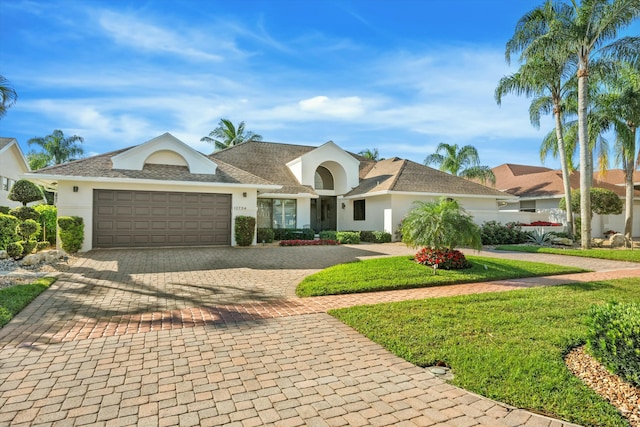 single story home with stucco siding, an attached garage, decorative driveway, and a front yard