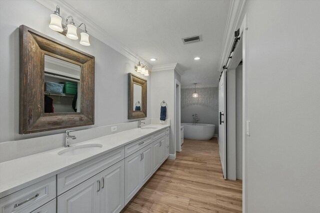 bathroom with double vanity, ornamental molding, wood finished floors, and a sink