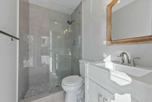 bathroom with tiled shower, toilet, and vanity