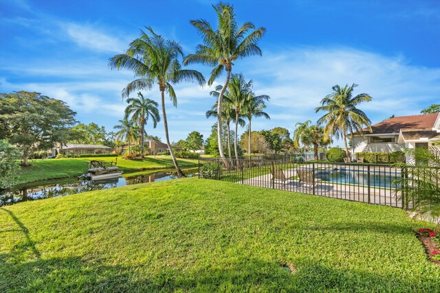 view of yard featuring a fenced in pool, a water view, and fence