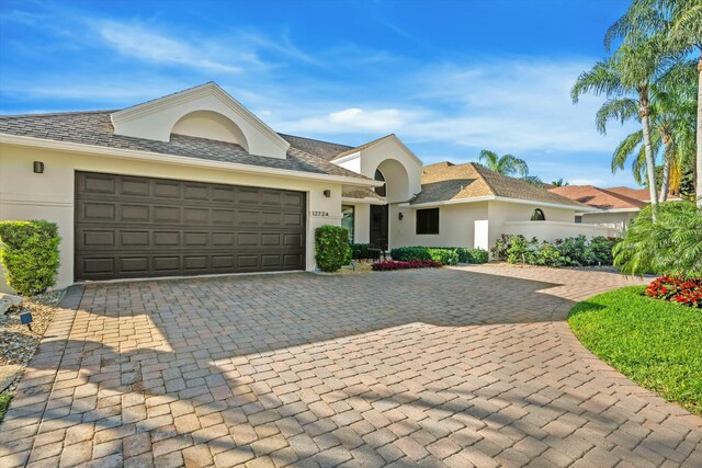 ranch-style house featuring stucco siding, decorative driveway, and a garage