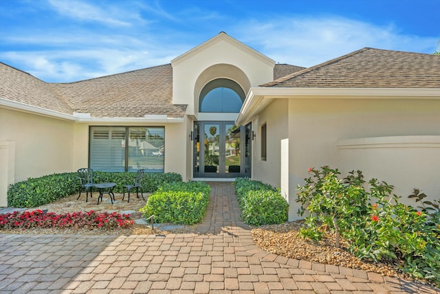 property entrance featuring stucco siding and a shingled roof