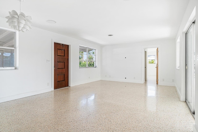 unfurnished room featuring light speckled floor and baseboards