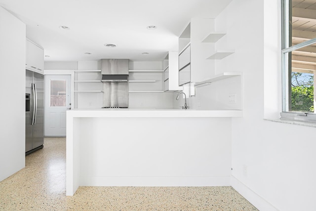 kitchen with open shelves, white cabinetry, a peninsula, wall chimney exhaust hood, and stainless steel fridge with ice dispenser