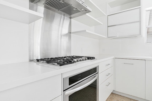 kitchen featuring premium range hood, light speckled floor, appliances with stainless steel finishes, white cabinets, and light countertops