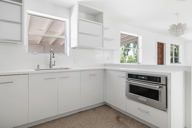 kitchen featuring open shelves, a sink, oven, light countertops, and light speckled floor