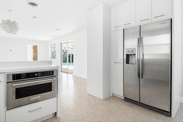 kitchen with visible vents, light countertops, stainless steel appliances, white cabinets, and light speckled floor