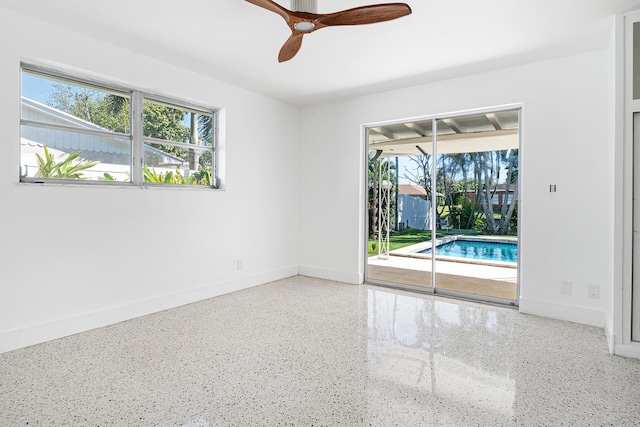 unfurnished room featuring speckled floor, baseboards, and a ceiling fan