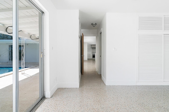 corridor with speckled floor and baseboards