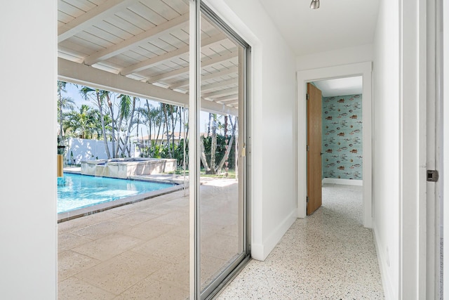 interior space with wallpapered walls, beamed ceiling, baseboards, and speckled floor