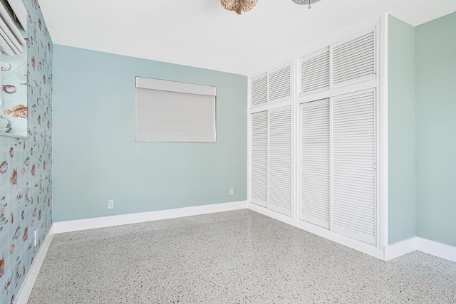 unfurnished bedroom featuring speckled floor, baseboards, and a closet