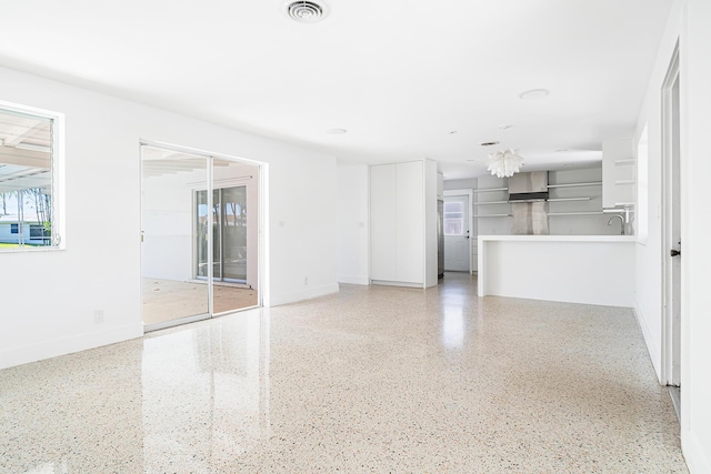 unfurnished living room featuring visible vents, speckled floor, and baseboards