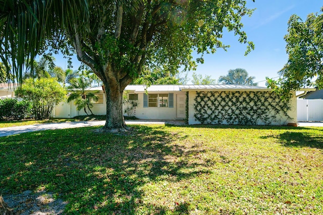 view of front of home with stucco siding, metal roof, a front yard, and fence