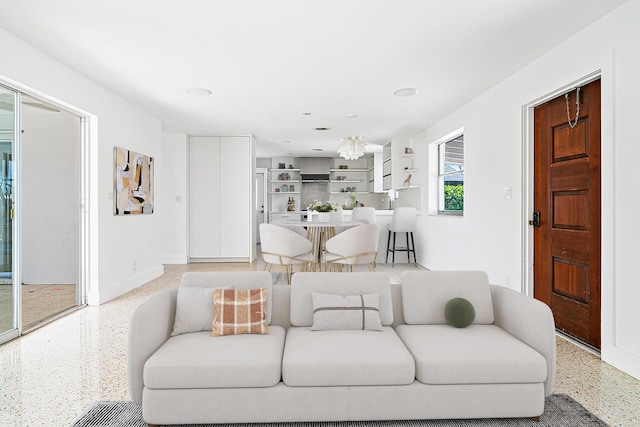 living area with speckled floor, baseboards, and an inviting chandelier