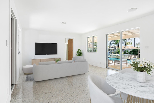 living room featuring visible vents, speckled floor, and baseboards