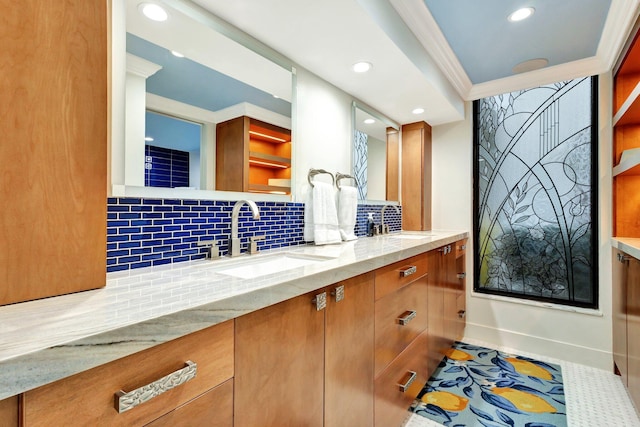 bathroom featuring decorative backsplash, double vanity, ornamental molding, and a sink