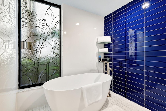 bathroom featuring tile patterned flooring, a soaking tub, and tile walls