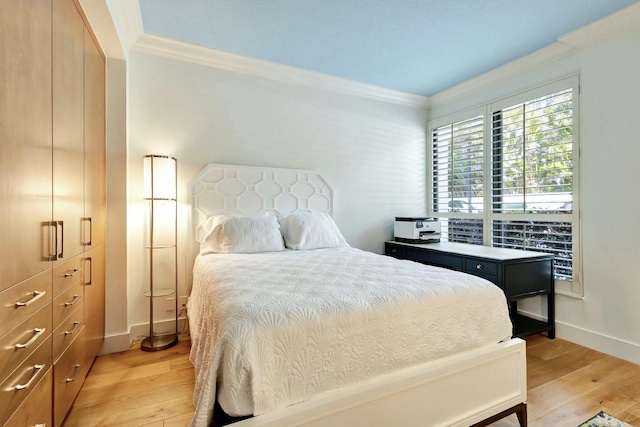 bedroom with crown molding, baseboards, and light wood finished floors