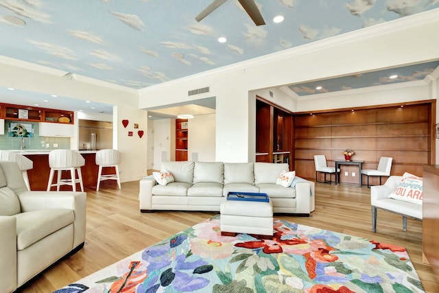 living area featuring a ceiling fan, crown molding, wood finished floors, and visible vents