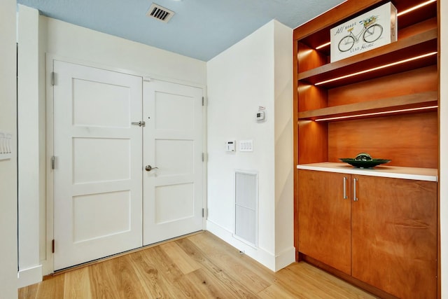 interior space with light wood finished floors, visible vents, and baseboards