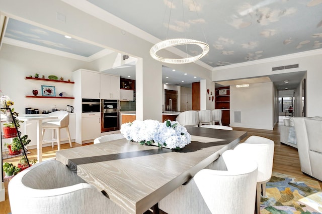 dining area with visible vents, crown molding, and light wood finished floors