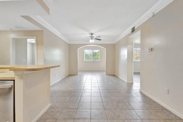 unfurnished living room with visible vents, ornamental molding, light tile patterned floors, arched walkways, and a ceiling fan