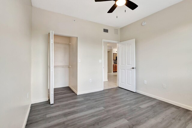 unfurnished bedroom featuring a ceiling fan, wood finished floors, baseboards, and a closet