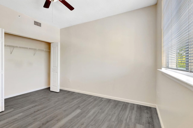 unfurnished bedroom with wood finished floors, visible vents, a closet, and baseboards