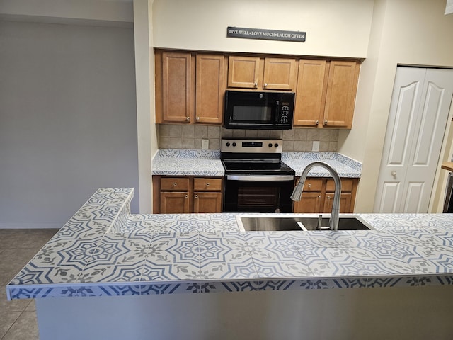 9833 Baywinds Dr Unit 7307, West Palm Beach, FL 33411 - kitchen featuring black microwave, range with electric stovetop, tasteful backsplash, and brown cabinetry