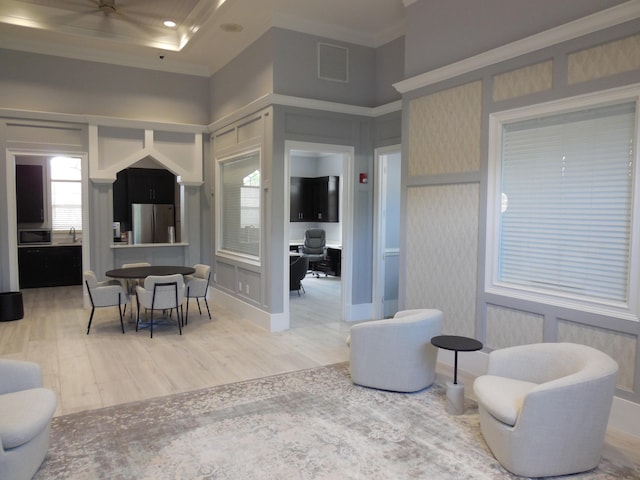 living room featuring a wealth of natural light, visible vents, light wood-style flooring, and crown molding