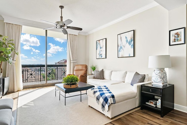 living area featuring crown molding, baseboards, expansive windows, wood finished floors, and a ceiling fan