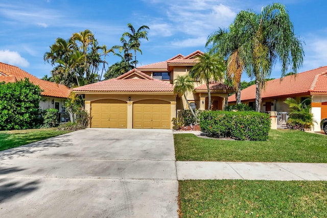 mediterranean / spanish-style home with stucco siding, a front lawn, concrete driveway, a garage, and a tiled roof