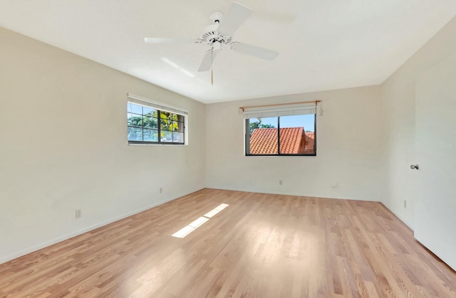 spare room with baseboards, plenty of natural light, light wood-style floors, and ceiling fan