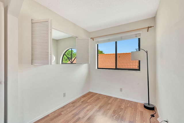 spare room with a textured ceiling, baseboards, and wood finished floors