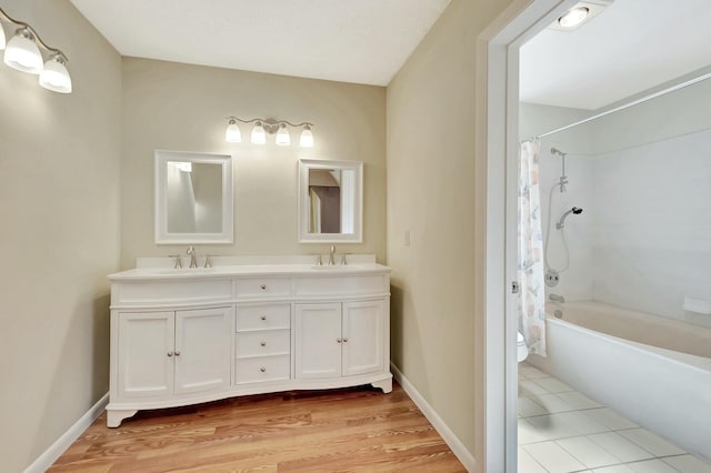 bathroom featuring double vanity, toilet, shower / tub combo with curtain, and a sink