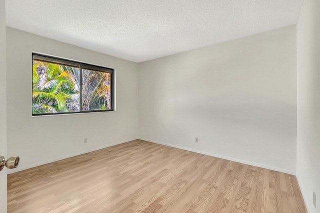 unfurnished room with baseboards, a textured ceiling, and light wood-style flooring