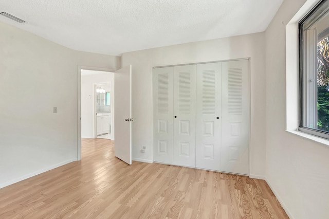 unfurnished bedroom with light wood-type flooring, baseboards, visible vents, and a closet