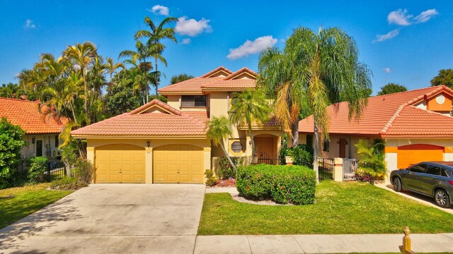 mediterranean / spanish home with stucco siding, a tile roof, concrete driveway, a front yard, and an attached garage