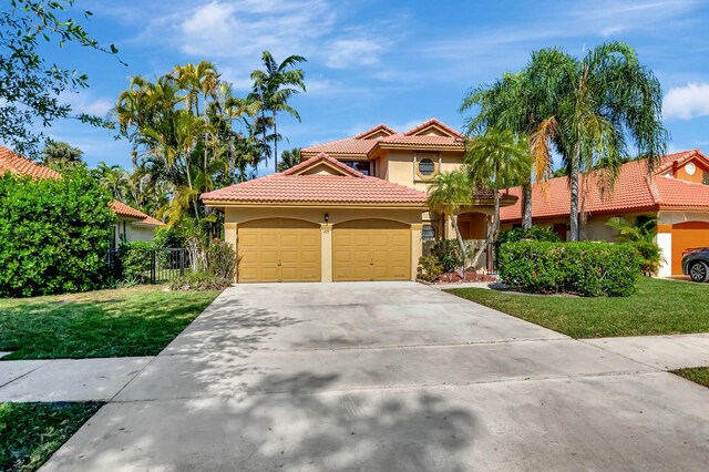 mediterranean / spanish house featuring stucco siding, a front lawn, driveway, a tile roof, and an attached garage